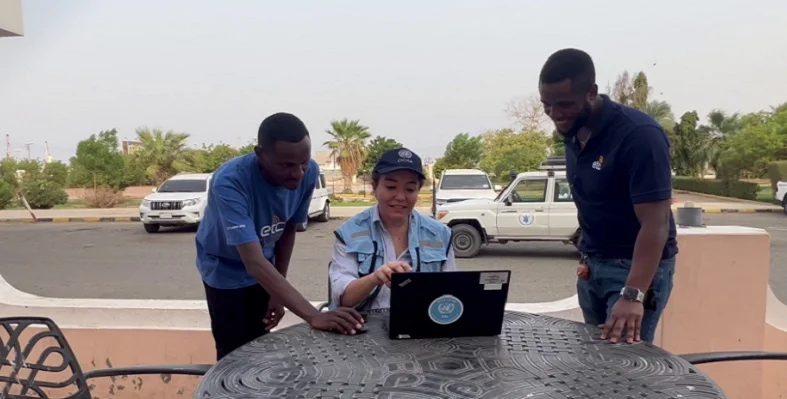 A person accessing the Internet on a laptop flanked by two onlookers