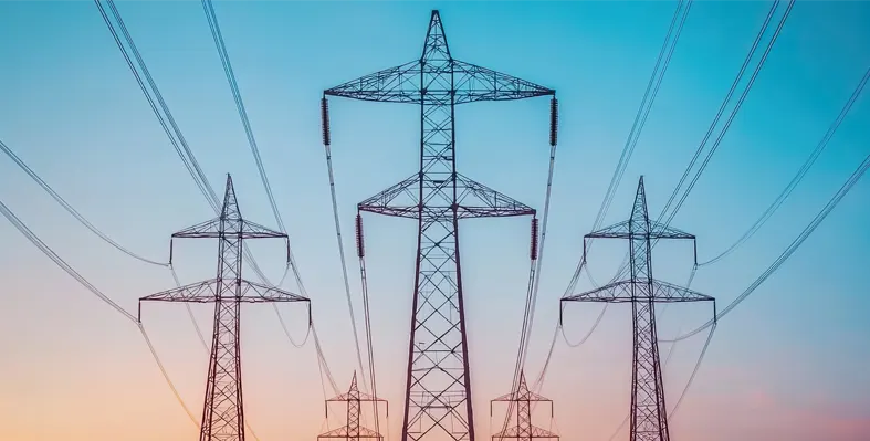 Power lines tower against a colorful sunset