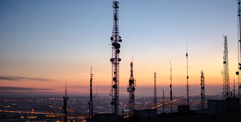 An image of telecom towers atop a mountain overlooking coastal lights