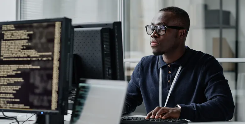 Young developer in eyeglasses working on computer.