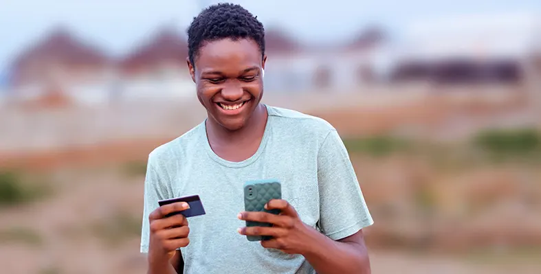 Young_man_shopping_smiling_at_phone_with_credit_card