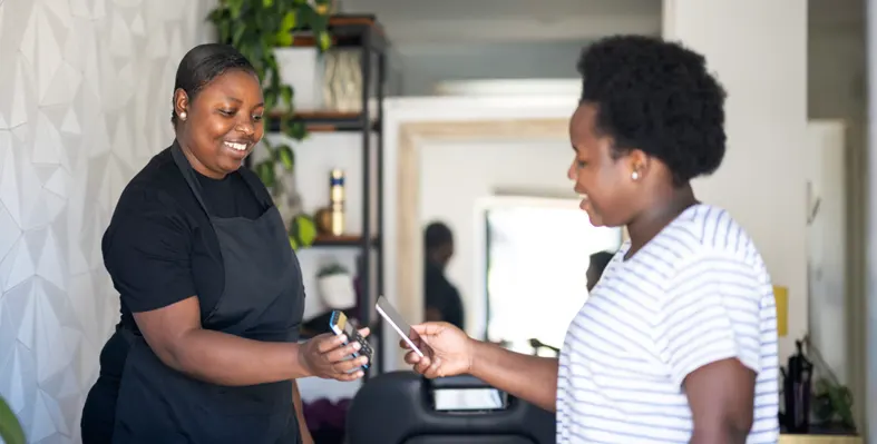 Two women exchanging payment using their smartphones at counter