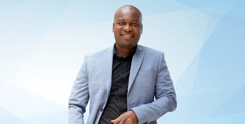 Sabelo Mwali smiles at the camera against a blue background