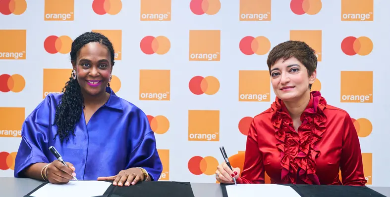 Aminata Kane and Amnah Ajmal sit at a table, signing a partnership agreement