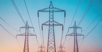 Power lines tower against a colorful sunset
