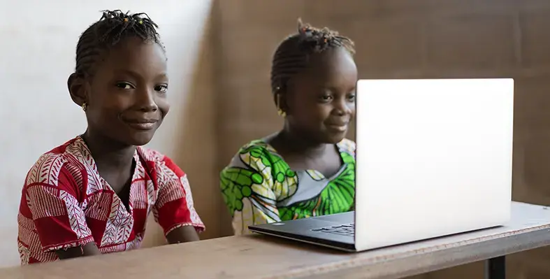 Two_children_sitting_and_operating_laptop