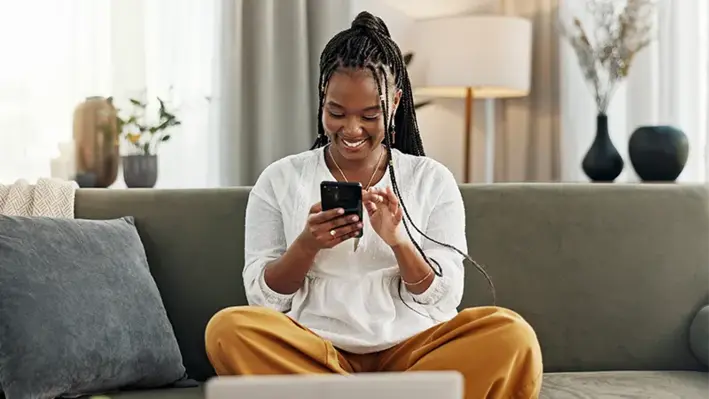 This collaboration will allow Bayobab to optimise SMS connectivity while significantly reducing administrative costs. (Image source: Adobe Stock) African_women_sitting_on_the_couch_while_scolling_phone