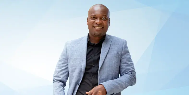Sabelo Mwali smiles at the camera against a blue background